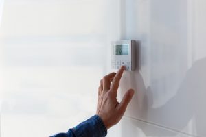 Ductless HVAC repair, man changing temperature on thermostat