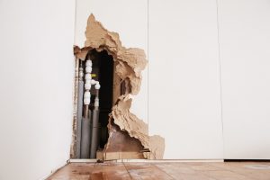 Damaged wall exposing burst water pipes